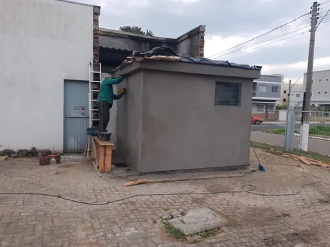 Profissional executando acabamento externo no abrigo de alvenaria