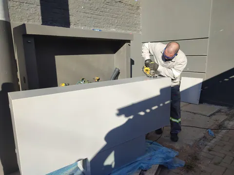 Profissional instalando o quadro na abertura do abrigo de alvenaria