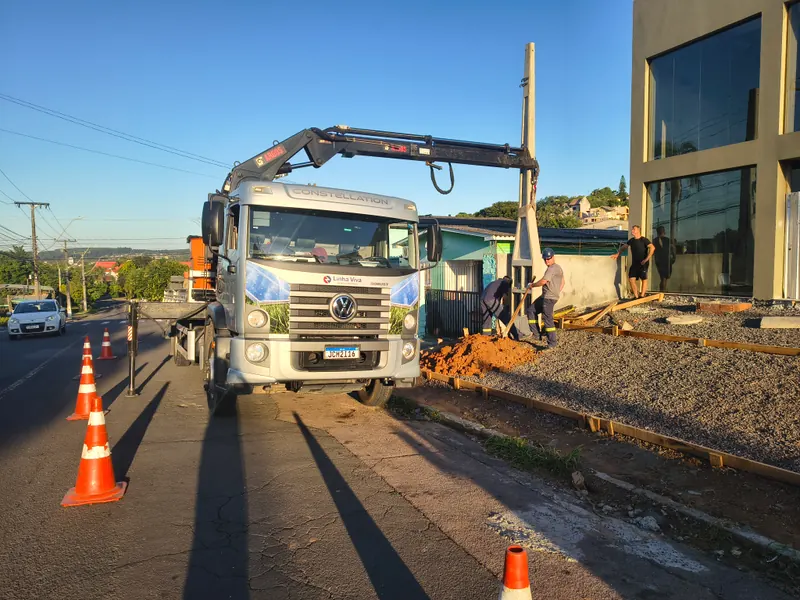 Equipe instalando poste padrão com auxílio de caminhão guindaste em frente ao imóvel