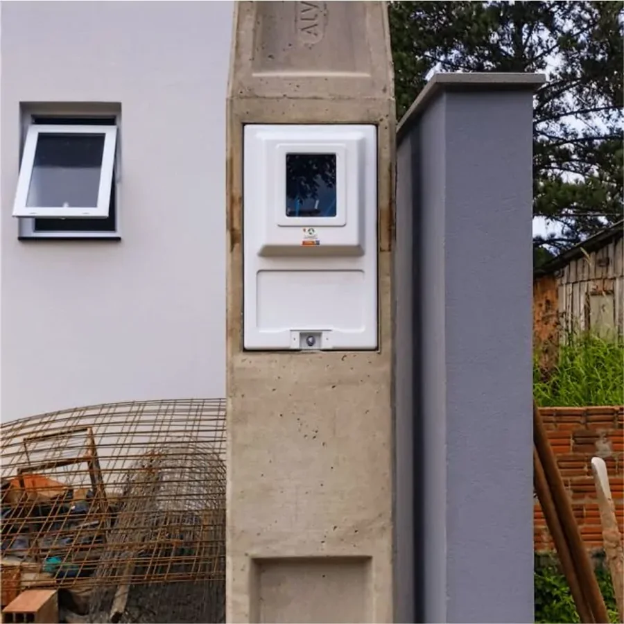 Caixa de medição em poste de concreto em frente a um imóvel