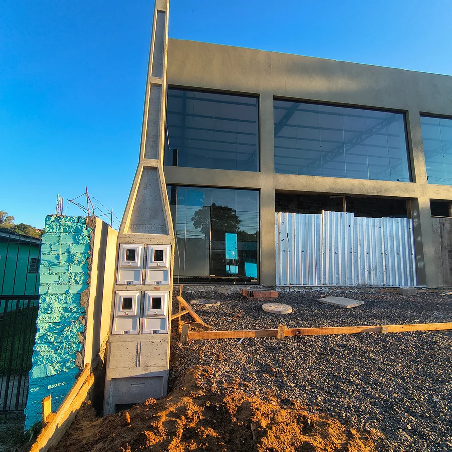 Poste de concreto com conjunto de caixas de medição em frente a uma edificação