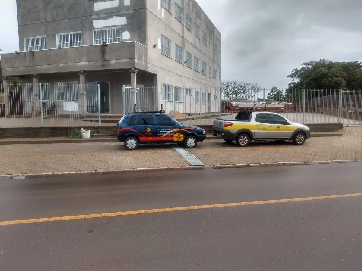 Veículos identificados com as marcas Linha Viva e L&M em frente a um prédio em 2016
