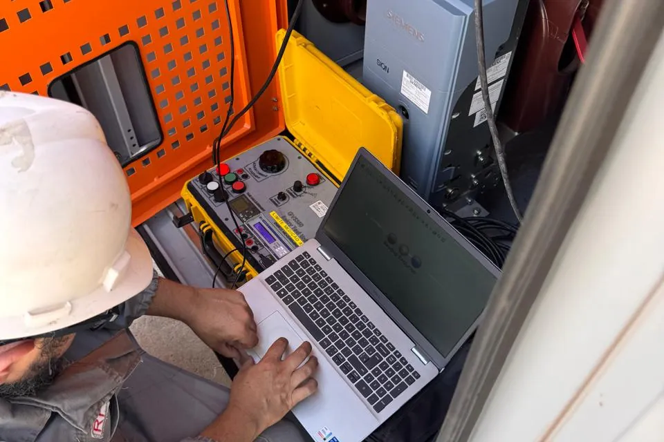 Profissional com notebook realizando avaliação junto a equipamento elétrico