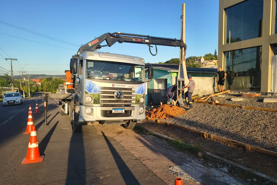 Equipe e caminhão guindaste na instalação de poste para entrada de energia