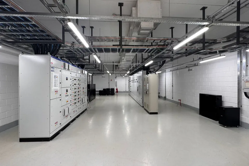 Sala elétrica com painéis industriais e infraestrutura de cabos no teto