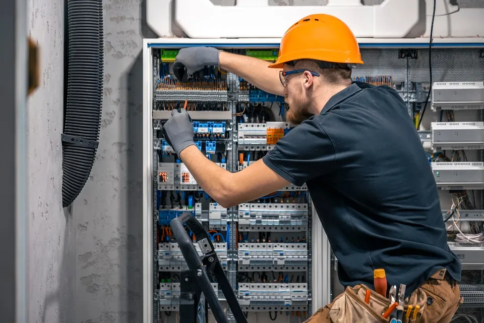 Eletricista trabalhando em quadro com dispositivos de proteção elétrica