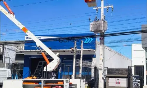 Equipe em cesto aéreo junto à rede elétrica e ao transformador no poste