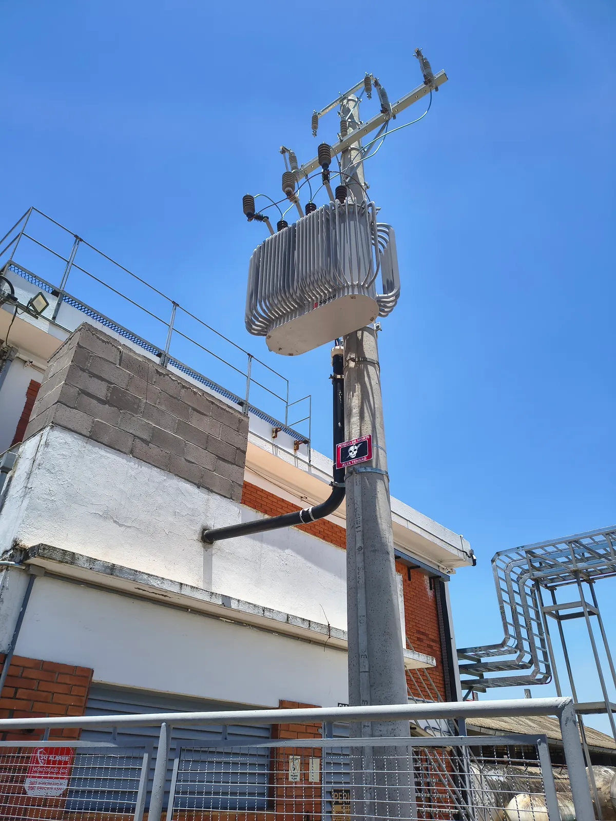 Transformador instalado em poste de concreto junto a um edifício