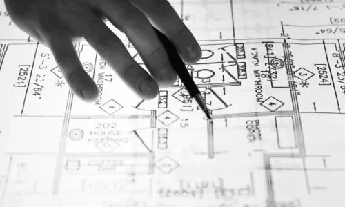 Mão com caneta sobre desenho de projeto elétrico
